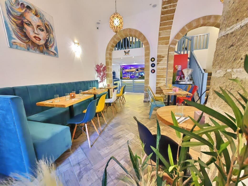 The main hall at Butterfly Space — teal velvet banquettes, a painted portrait, stone arches and herringbone floors